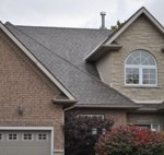 image of a suburban house with large windows and a double car garage, new shingled roof installed by Baron Roofing & Siding
