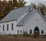 image of a small white church with a new shingled roof, installed by Baron Roofing & Siding